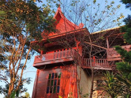 a red building with a balcony on top of it at Rai Phuchat in Ban Pa Thon