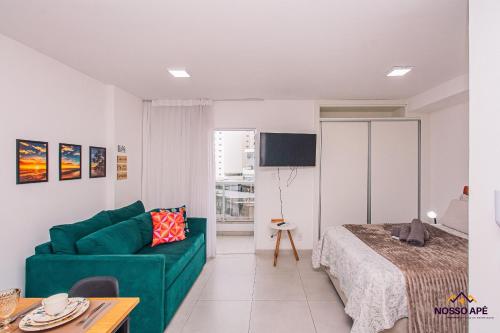 a living room with a green couch and a bed at Nosso Apê 915: Ar-condicionado | Piscina - NA0812 in Juiz de Fora