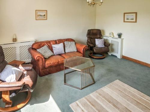 a living room with a leather couch and two chairs at Lupton Hall Cottages in Lupton