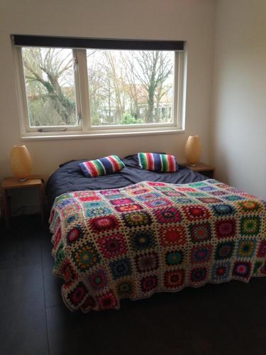 a bedroom with a bed with a colorful blanket and a window at Suite School 15 A in Zonnemaire