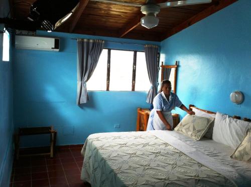 a man sitting on a bed in a blue room at Hotel Caribe in Santa Cruz de Barahona