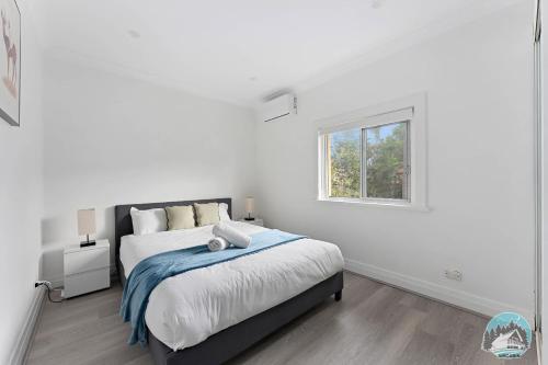 a white bedroom with a bed and a window at Stylish 4-Bed Loft in Manly Walk to Beach & Ferry in Sydney