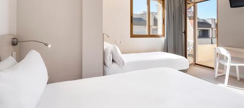 two white beds in a room with a window at Hotel Andalucía in Benidorm