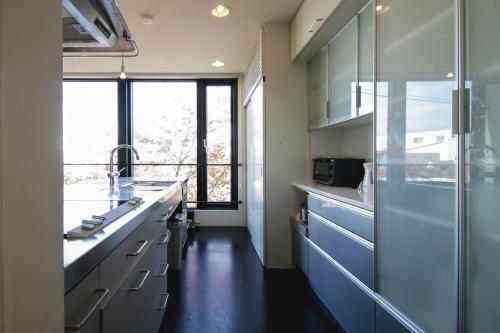 a kitchen with blue cabinets and a large window at Townhouse Asahikawa in Asahikawa