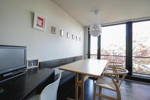a living room with a table and chairs and a television at Townhouse Asahikawa in Asahikawa