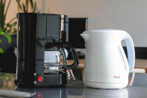 a black and white appliance sitting on a counter next to a cup at Townhouse Asahikawa in Asahikawa