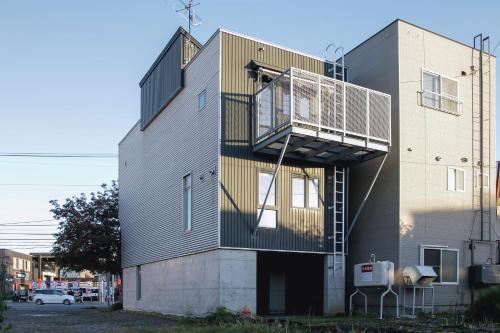 a building with a balcony on the side of it at Townhouse Asahikawa in Asahikawa