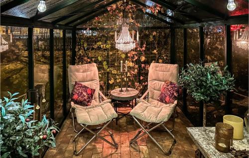 a greenhouse with two chairs and a table and a chandelier at Nice Home In Hjältevad With Sauna in Hjältevad