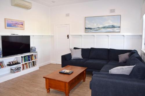a living room with a blue couch and a coffee table at Christina Cottage - Bring your own linen in South West Rocks