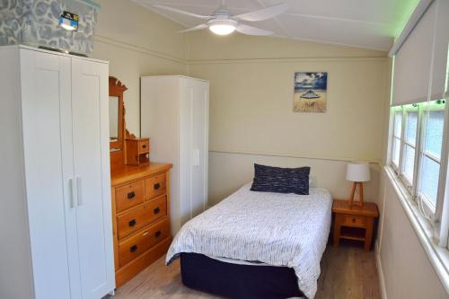 ein Schlafzimmer mit einem Bett und einem Deckenventilator in der Unterkunft Christina Cottage - Bring your own linen in South West Rocks