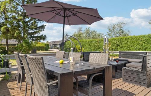 a wooden table with an umbrella on a deck at Amazing Home In Dannemare With Kitchen in Dannemare
