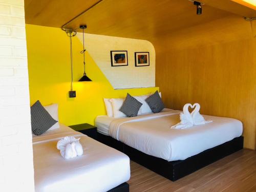 two beds in a room with yellow walls at Chick Resort Khao Kho in Khao Kho