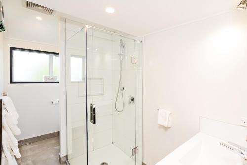 a white bathroom with a glass shower stall at Balmoral Lodge Motel in Invercargill