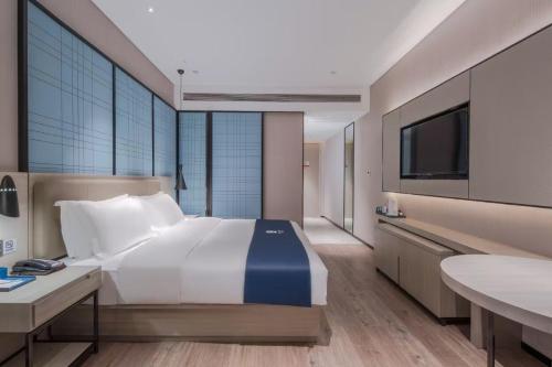 una camera da letto con un letto grande e una televisione di Echarm Hotel Nanning East Railway Station a Tunli