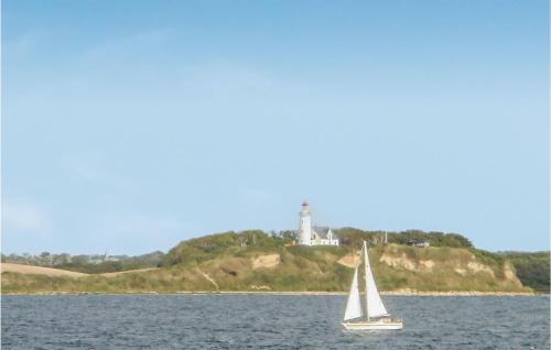 a sailboat in the water with a lighthouse in the background at Stunning Apartment In Samsø With Wifi in Kolby Kås