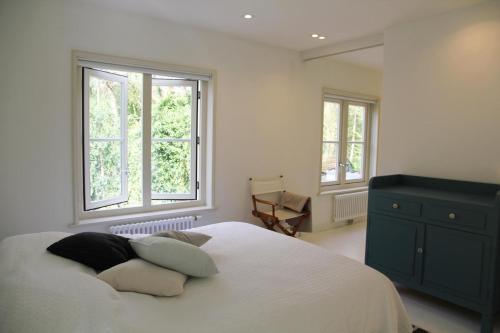 a bedroom with a white bed and two windows at Het Bosch in Bergen