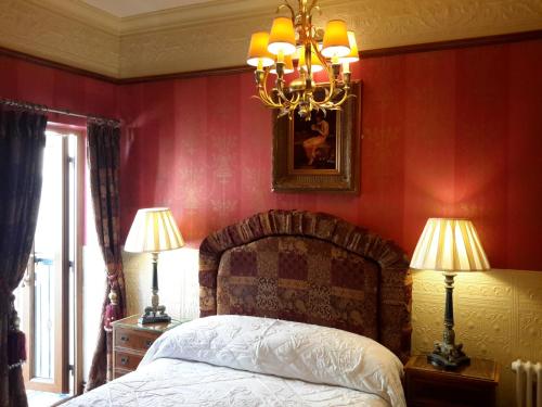 a bedroom with a bed with red walls and a chandelier at The Lonsdale in Blackpool