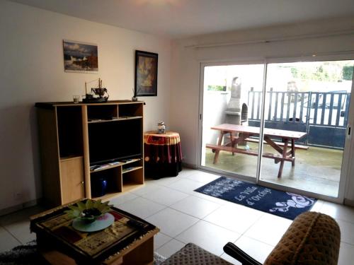 un salon avec une télévision et une table dans l'établissement Les Gîtes Bleus de Lannion - avec cuisine-, à Lannion