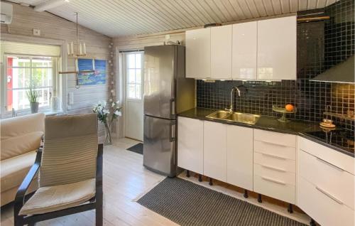 a kitchen with white cabinets and a stainless steel refrigerator at Amazing Home In Boxholm in Boxholm