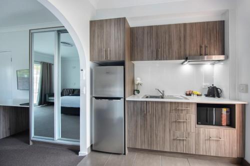 a kitchen with a stainless steel refrigerator and a bedroom at Hamilton's Queanbeyan Motel in Queanbeyan