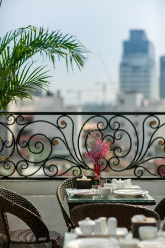 a table with chairs and a vase of flowers on a balcony at Dream Premium Hotel & Spa in Hanoi