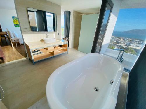 a bathroom with a large white tub and a sink at Anh Nguyen Oceanfront Luxury Villas Nha Trang in Nha Trang
