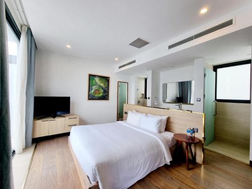 a bedroom with a white bed and a flat screen tv at Anh Nguyen Oceanfront Luxury Villas Nha Trang in Nha Trang