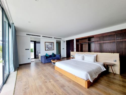 a bedroom with a large bed and a blue couch at Anh Nguyen Oceanfront Luxury Villas Nha Trang in Nha Trang