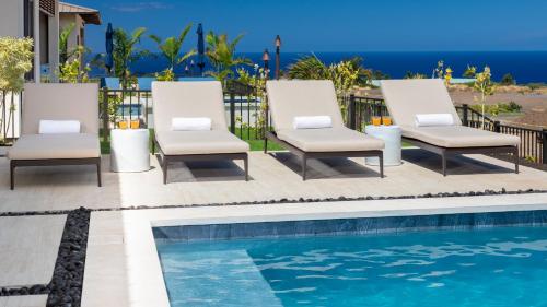 a pair of lounge chairs next to a swimming pool at MAUNA KEA BEACH ESCAPE Luxurious home in private community with Heated Private Pool and Spa Detached Ohana Suite in Waimea