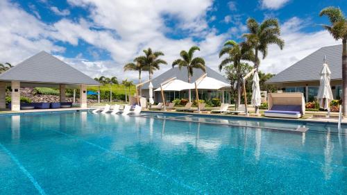 a pool at a resort with chairs and palm trees at MAUNA KEA BEACH ESCAPE Luxurious home in private community with Heated Private Pool and Spa Detached Ohana Suite in Waimea