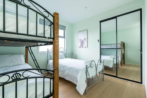a bedroom with two bunk beds and a mirror at Newly built with WiFi & Healthclub, pool & gym access in Inverloch