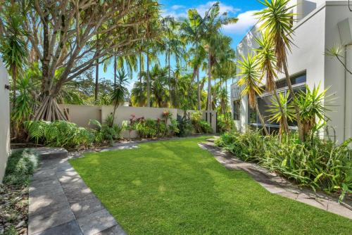 a garden with a lawn and palm trees at Villa 8 The Lakes in Yaroomba