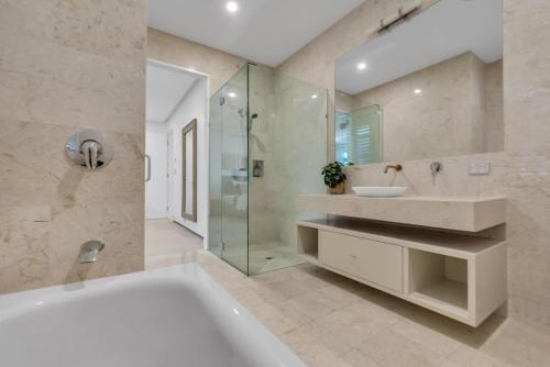 a bathroom with a tub and a sink and a shower at Villa 8 The Lakes in Yaroomba