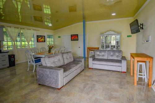 a living room with two couches and a table and a dining room at Alojamiento campestre villa Gabriela filandia in Filandia