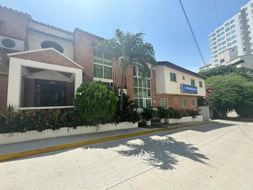 a brick building with a palm tree in front of a street at Hotel Rodadero Relax in Gaira