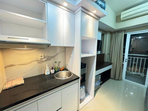 a kitchen with white cabinets and a sink at Taman Melati Yogyakarta Apartement 1240 in Kejayan