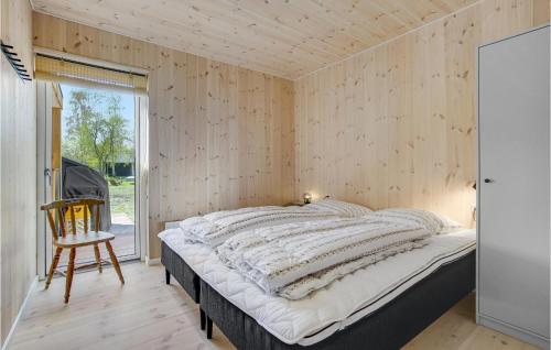 a bedroom with a bed and a wooden wall at Beautiful Home In Sjællands Odde With 5 Bedrooms in Yderby