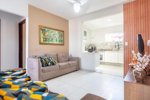 a living room with a couch and a kitchen at Refúgio Tropical Casa de Praia com Piscina Climatizada e 4 Suítes e garagem 3 carros, 800 mtrs da praia internet 700 mbps, condomínio privado com pista de skate , quadra de futevôlei , campos e quadras de futebol! in Cabo Frio