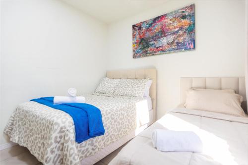 a bedroom with two beds and a painting on the wall at Refúgio Tropical Casa de Praia com Piscina Climatizada e 4 Suítes e garagem 3 carros, 800 mtrs da praia internet 700 mbps, condomínio privado com pista de skate , quadra de futevôlei , campos e quadras de futebol! in Cabo Frio