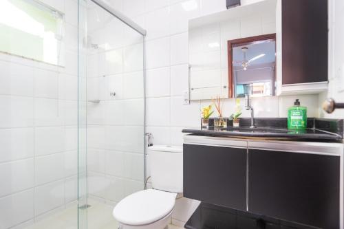 a bathroom with a toilet and a glass shower at Refúgio Tropical Casa de Praia com Piscina Climatizada e 4 Suítes e garagem 3 carros, 800 mtrs da praia internet 700 mbps, condomínio privado com pista de skate , quadra de futevôlei , campos e quadras de futebol! in Cabo Frio