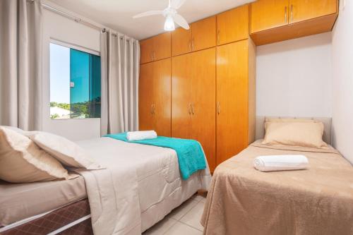 a bedroom with two beds and wooden cabinets at Refúgio Tropical Casa de Praia com Piscina Climatizada e 4 Suítes e garagem 3 carros, 800 mtrs da praia internet 700 mbps, condomínio privado com pista de skate , quadra de futevôlei , campos e quadras de futebol! in Cabo Frio