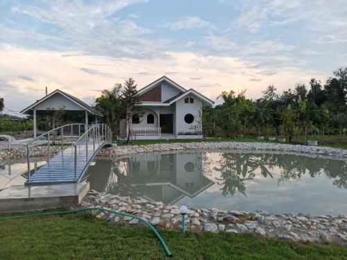 a house with a pond in front of it at Numhom Resort in Ban Nong Chum Saeng