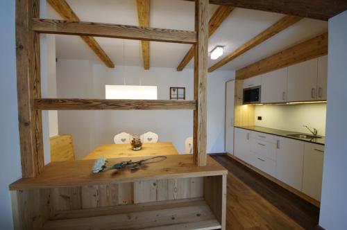 una cucina con tavolo in legno in una camera di Chalet Apartments Ambria a La Villa