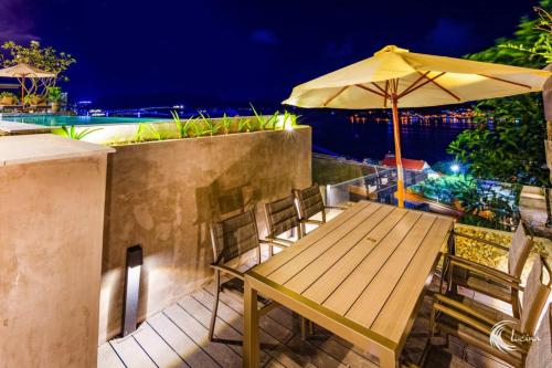 a wooden table and chairs with an umbrella at Anh Nguyen Oceanfront Luxury Villas Nha Trang in Nha Trang