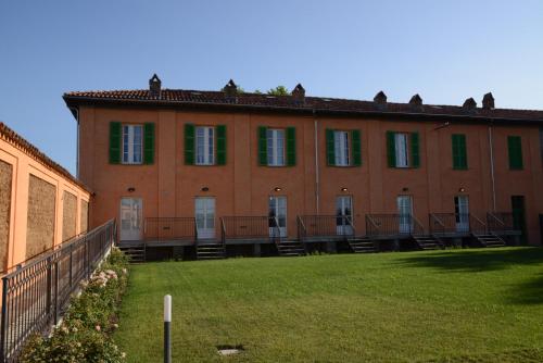 a large brick building with green windows and a yard at Tenuta La Fiscala in Alessandria