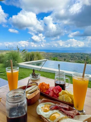 une table avec de quoi petit-déjeuner et deux verres de jus d'orange dans l'établissement EDEN Eco-Villas with Private Pool and Panoramic Sea View - ADULT ONLY, à Nusa Penida