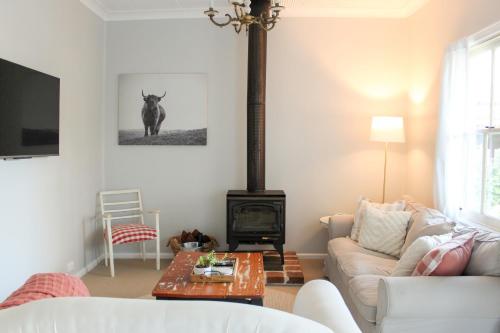 a living room with a couch and a stove at The Little White Cottage - Country Elegance Near CBD in Mudgee