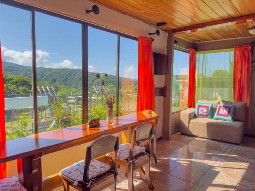 a dining room with a table and chairs and large windows at Lidia's Mountain View Vacation Homes in Monteverde Costa Rica