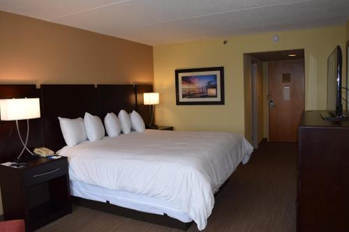 una habitación de hotel con una cama grande con sábanas blancas en BridgePointe Hotel & Marina en New Bern