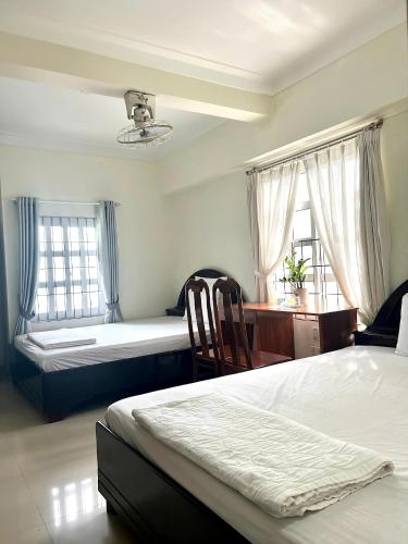 a bedroom with two beds and a desk and two windows at Blue Sea 01 Hotel in Nha Trang
